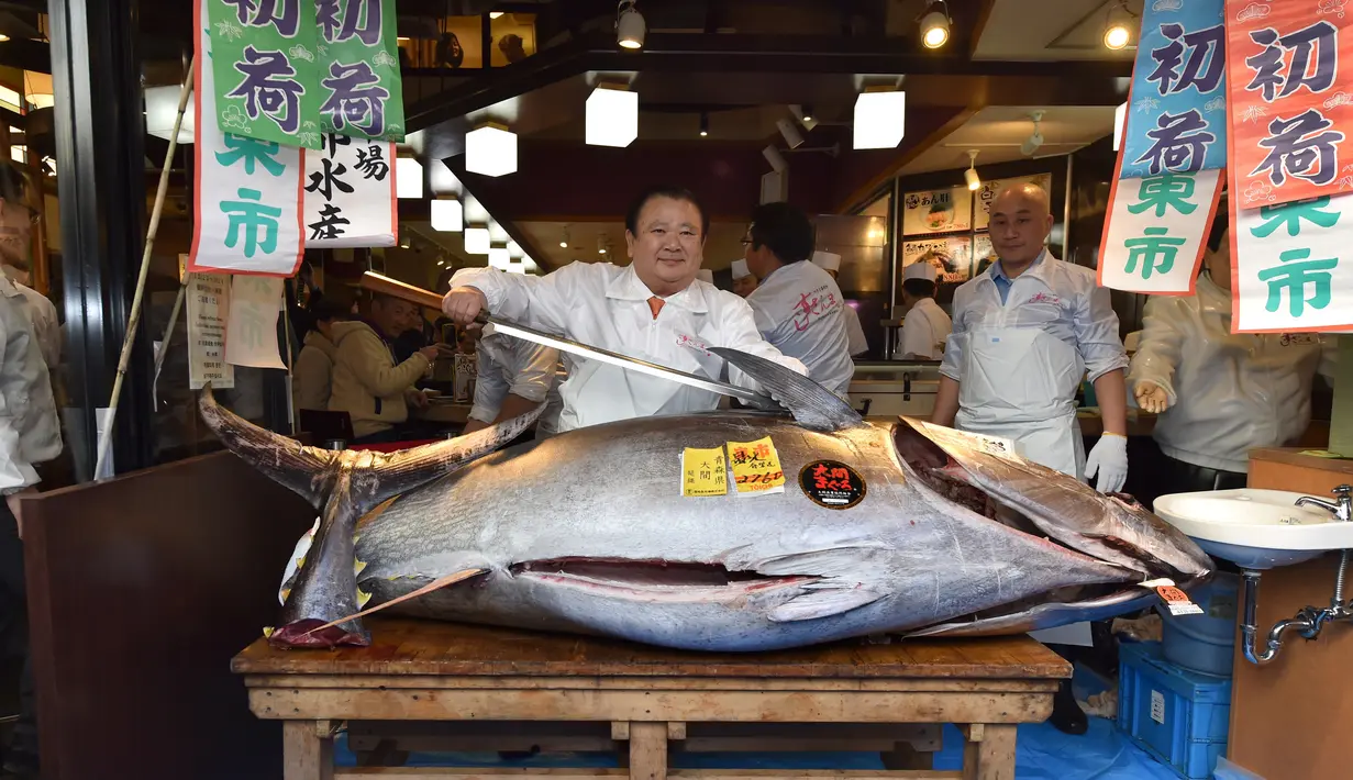 Pengusaha restoran sushi Jepang, Kiyoshi Kimura berpose dengan pedang sebelum mengiris  tuna sirip biru seberat 276 kg di restoran utamanya di Tokyo, Minggu (5/1/2020). Tuna seharga Rp 24 miliar itu disebut sebagai yang tertinggi kedua dalam rekor lelang ikan di Pasar Toyosu. (Kazuhiro NOGI / AFP)
