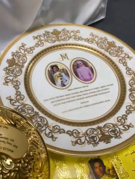 Setiap tamu undangan juga menerima piring hiasan warna putih dengan ukiran warna emas di sekelilingnya. Pada bagian tengah, terlihat foto Pangeran Mateen dan Anisha Rosnah. [Foto: TikTok/yourgoodbyevideo]