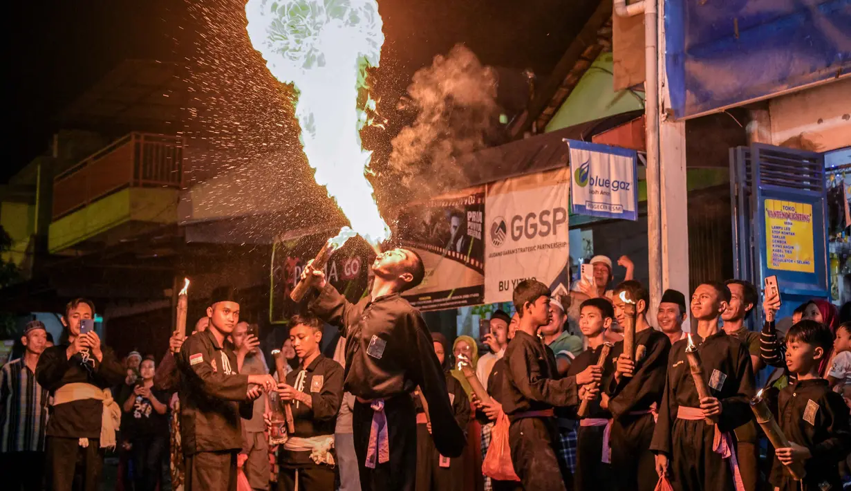 Seorang pemuda Muslim Indonesia melakukan aksi menghembuskan api saat parade yang menandai dimulainya tahun baru Islam di Surabaya, Jawa Timur pada Kamis 26 Juni 2025 malam. (Juni KRISWANTO/AFP)