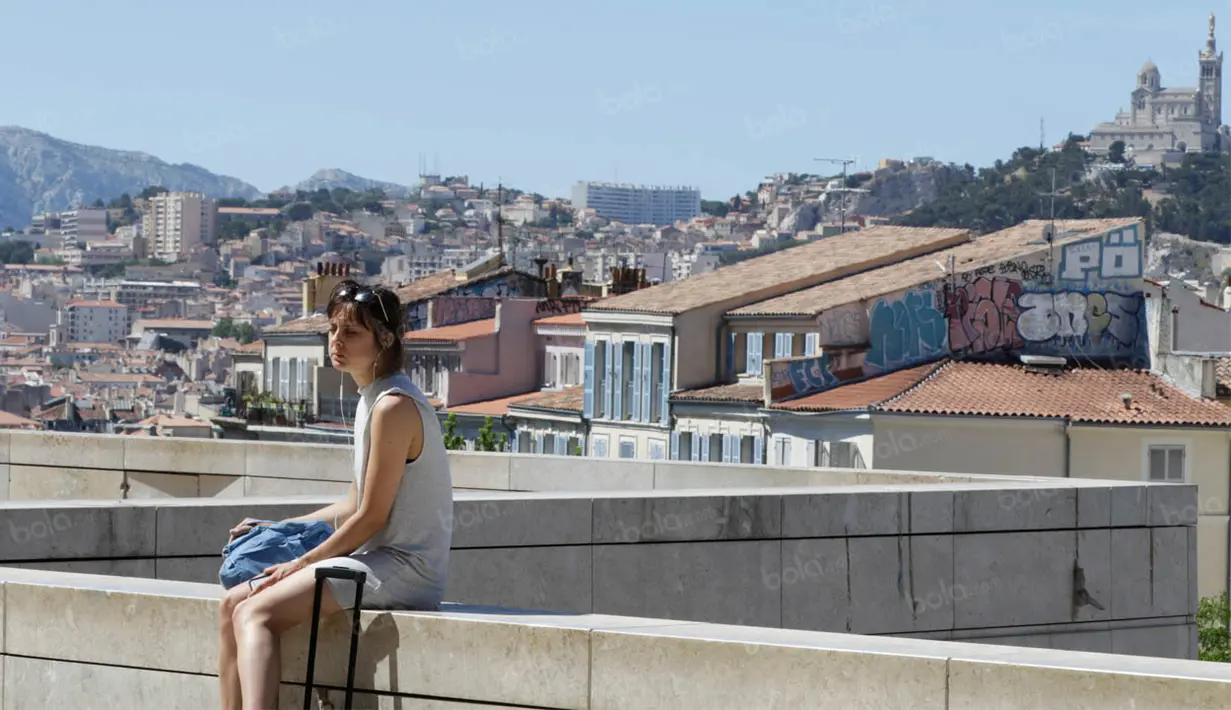 Seorang wanita duduk dengan latar belakang suasana kota di Marseille, Prancis, Minggu (3/7/2016). Marseille merupakan daerah pesisir di selatan Prancis dengan pesona keindahan alam. (Bola.com/Vitalis Yogi Trisna)