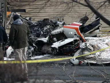 Warga melihat puing-puing pesawat pribadi yang jatuh di kawasan perumahan Roy, Utah, Amerika Serikat, Rabu (15/1/2020). Seorang pilot berusia 64 tahun dilaporkan tewas. (Ben Dorger/Standard-Examiner, via AP)