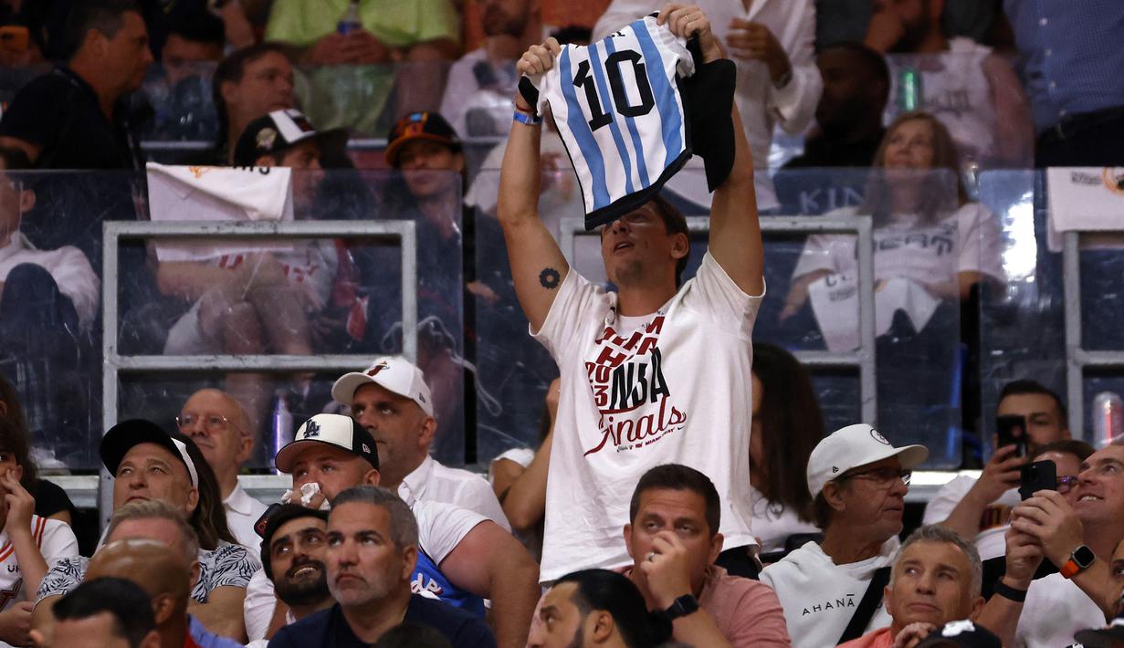 Seorang pendukung klub basket, Miami Heat memegang jersey Lionel Messi saat game ketiga Final NBA 2023 melawan Denver Nuggets di Kaseya Center, Miami, Florida, Amerika Serikat, 7 Juni 2023. Messi memutuskan untuk bergabung dengan klub MLS, Inter Miami, pada Rabu (7/6/2023). (AFP/Giorgio Viera)