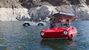 Mobil amfibi Panther WaterCar (kiri), yang dikemudikan Bob Davis dan Amphicar 1963, dikemudikan Rob Vondracek saat festival Las Vegas Amphicar Swim di Danau Mead, Nevada, Jumat (9/10). (REUTERS/Steve Marcus)