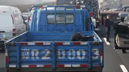 Seorang pengendara terlihat tidur di bak kendaraannya saat terjebak kemacetan parah di Jinji Expressway, antara Beijing-Tianjin, China, Rabu (2/3). (REUTERS/Kim Kyung - Hoon)