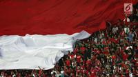 Suporter Timnas Indonesia membentangkan bendera raksasa saat menyaksikan laga persahabatan antara Indonesia melawan Fiji di Stadion Patriot Candrabhaga, Bekasi, Sabtu (9/2). Laga berakhir imbang 0-0. (Liputan6.com/Helmi Fithriansyah)