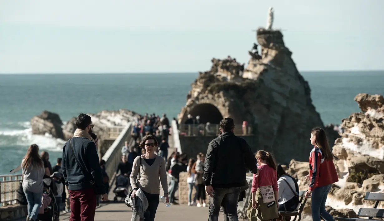 Warga dan turis menikmati cuaca musim dingin yang hangat saat berjalan di sepanjang garis pantai di Biarritz, Perancis (17/2). Kota ini terletak di region Aquitane, Departemen Pyrénées-Atlantiques. (AFP Photo/Iroz Gaizka)