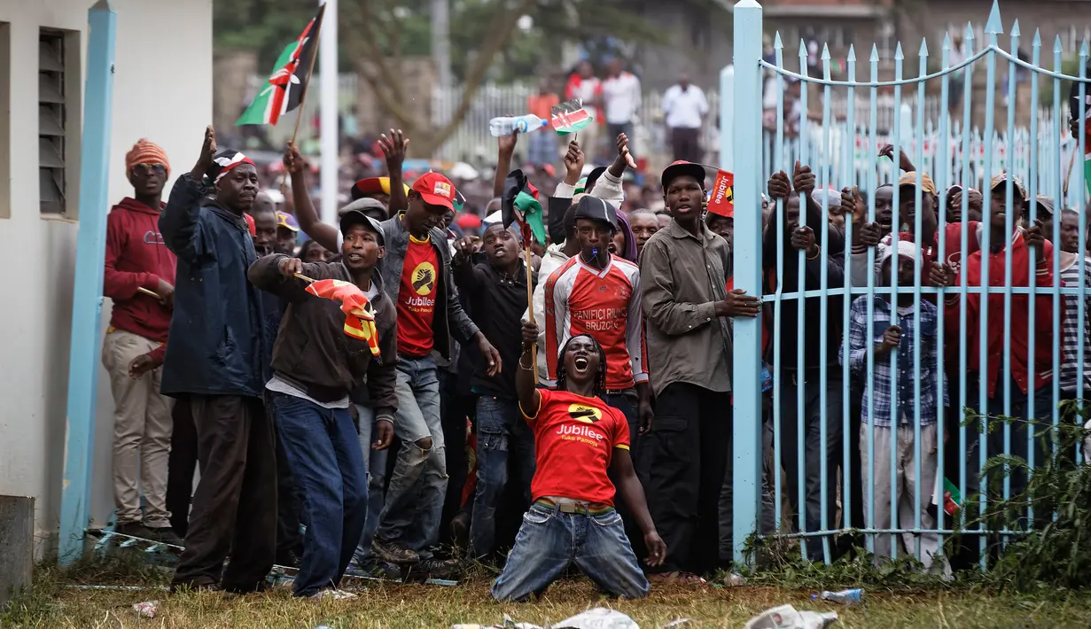 Pendukung Presiden Uhuru Kenyatta berdiri di depan gerbang saat pelatikan Presiden Kenya Uhuru Kenyatta di Nairobi, Kenya (28/11). Para pendukung ini memaksa masuk untuk mengikuti pelantikan Presiden Kenya Uhuru Kenyatta. (AP Photo / Ben Curtis)