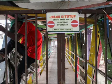 Seorang warga memanjat pagar Jembatan Penyeberangan Orang (JPO) yang menghubungkan daerah Rawajati dengan Cililitan di Jalan Raya Kalibata, Jakarta Selatan, Rabu (5/2/2025). (Magang/Liputan6.com/Muhammad Rizal)