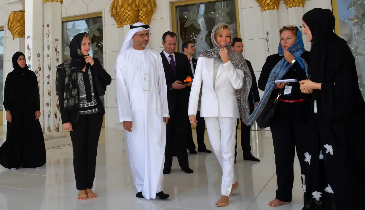 Istri Presiden Prancis, Brigitte Macron (ketiga kanan) mengunjungi Masjid Sheik Zayed di Abu Dhabi, Kamis (9/11). Di masjid tersebut, Brigitte terlihat mengenakan penutup kepala bermotif leopard dan melepas sepatu. (Giuseppe CACACE / AFP)