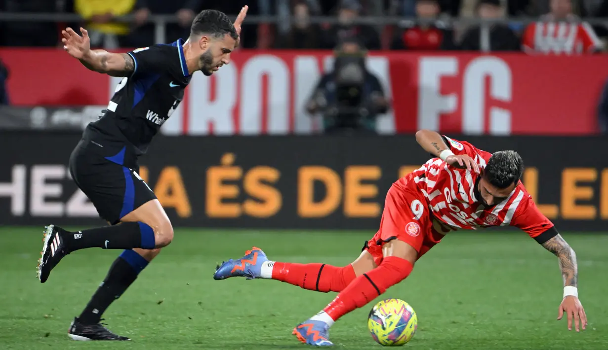 Pemain Atletico Madrid Mario Hermoso (kiri) bersaing memperebutkan bola dengan pemain Girona Taty Castellanos pada pertandingan sepak bola Liga Spanyol di Stadion Montilivi, Girona, Spanyol, 13 Maret 2023. Gol tunggal Alvaro Morata membawa Atletico Madrid mengalahkan Girona. (LLUIS GENE/AFP)
