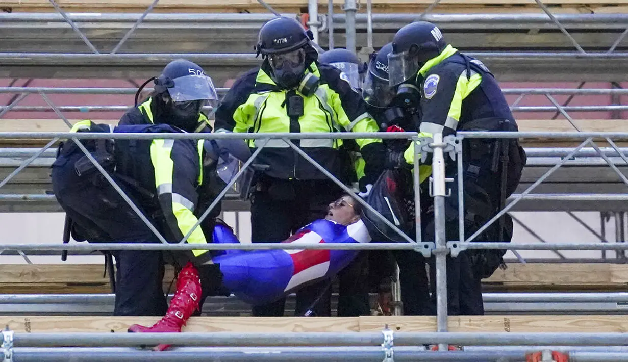 Polisi membawa massa pendukung Presiden Amerika Serikat Donald Trump saat kerusuhan di Capitol Hill, Washington, Amerika Serikat, Rabu (6/1/2021). Sejauh ini polisi Capitol menahan sekitar 20 orang perusuh. (AP Photo/John Minchillo)