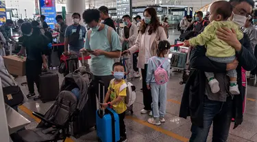 Orang-orang mengantre check-in untuk penerbangan domestik menjelang liburan "Golden Week" di Bandara Internasional Ibu Kota Beijing pada 30 September 2020. Gelombang liburan melanda China yang warganya merayakan libur panjang, yang dikenal dengan Golden Week. (NICOLAS ASFOURI / AFP)