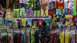 Pedagang gamis dan baju anak menunggu pembeli di kiosnya di pasar Parung, Bogor, Jawa Barat, Kamis (18/2/2021). Dampak pandemi COVID-19 yang berkepanjangan pedagang mengaku omset penjualan gamis dan baju anak turun 85 persen semenjak awal tahun lalu hingga sekarang. (Liputan6.com/Johan Tallo)