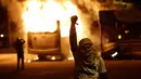 Seorang demonstran berada di dekat bus yang dibakar saat bentrokan dengan polisi dalam unjuk rasa di de Janeiro, Brasil, (29/4). Mereka menentang usulan perubahan undang-undang ketenagakerjaan dan sistem pensiun. (AP Photo/Leo Correa)