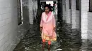 Seorang wanita berjalan di koridor rumah sakit yang tergenang banjir di Nalanda Medical College Hospital, daerah Bihar, India, 29 Juli 2018. Rumah sakit itu digenangi air kotor dengan sejumlah ikan terlihat berenang memenuhi lantai. (AFP PHOTO)