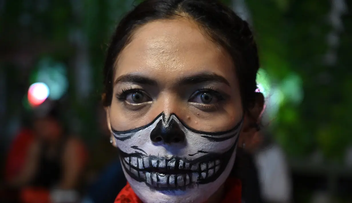 Seorang wanita melukis wajahnya saat pesta Halloween di sebuah kafe di Tangerang (31/10/2021). (AFP/Adek Berry)