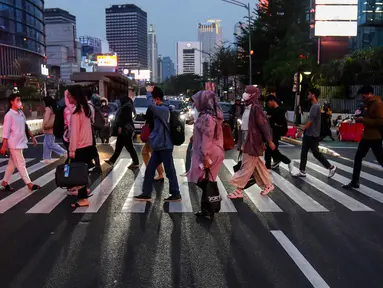 Pekerja saat melintas trotoar di kawasan Jend Sudirman, Jakarta, Selasa (21/11/2023). (Liputan6.com/Herman Zakharia)