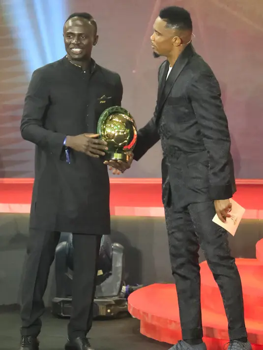 Mantan penyerang Kamerun Samuel Eto'o (kanan) memberi selamat kepada penyerang Senegal Sadio Mane (kiri) setelah memenangkan penghargaan Pemain Terbaik Afrika 2019 selama CAF Awards di kota wisata Mesir, Hurghada (7/1/2020). (AFP/Khaled Desouki)