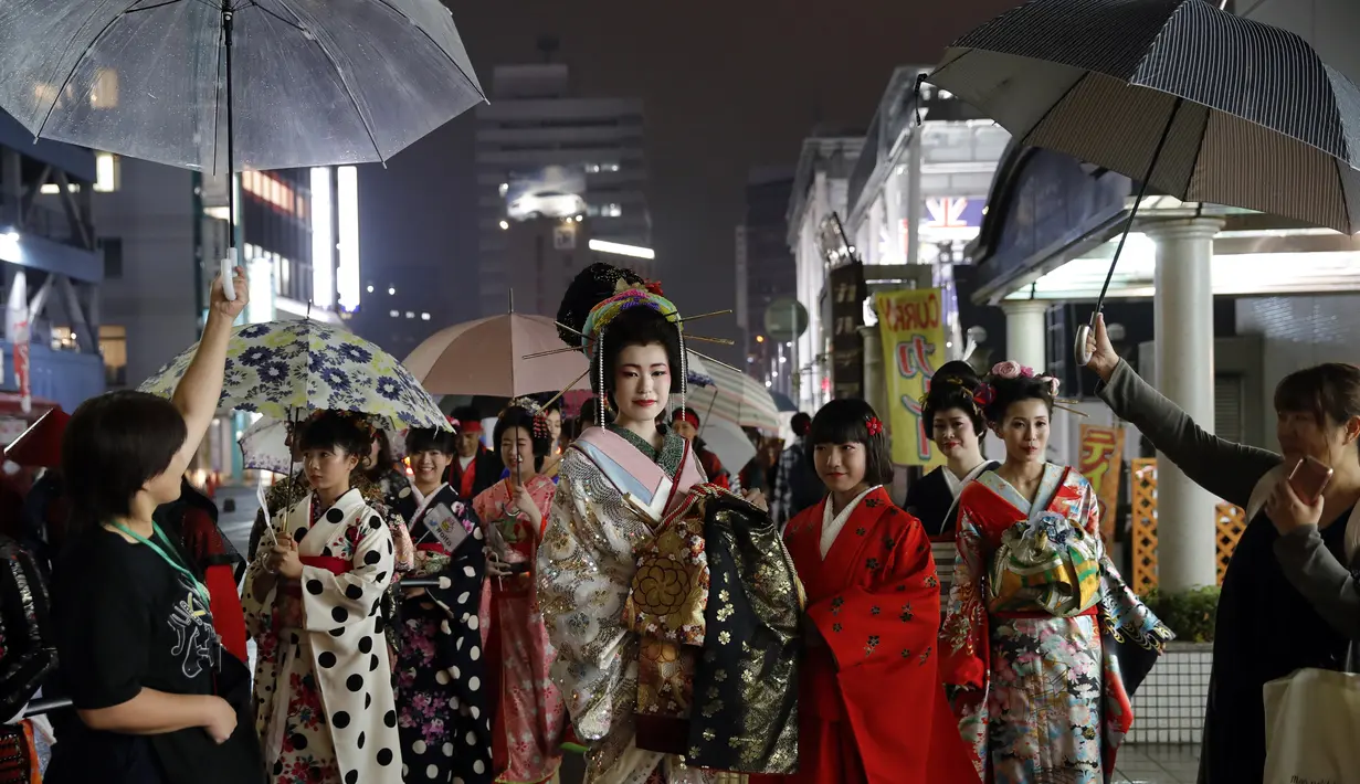 Sejumlah wanita Jepang berjalan di jalan setelah menghadiri peragaan busana kimono di Oita (18/10/2019). Sebutan lain untuk kimono adalah gofuku. Istilah gofuku mulanya dipakai untuk menyebut pakaian orang negara Dong Wu yang tiba di Jepang dari daratan China. (AP Photo/Christophe Ena)