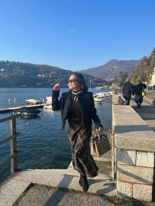 Berpose di Lake Como Italia, Prilly tampil elegan dengan tweed blazer warna hitam dan rok wol motif kotak-kotak. [@prillylatuconsina96]