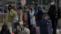 Pelancong yang mengenakan masker menunggu transportasi mereka di dekat stasiun kereta api di Beijing, Kamis (6/10/2022). Xinjiang yang luas adalah wilayah China terbaru yang terkena pembatasan perjalanan COVID-19, karena China semakin meningkatkan langkah-langkah pengendalian menjelang kongres penting Partai Komunis akhir bulan ini. (AP Photo/Andy Wong)