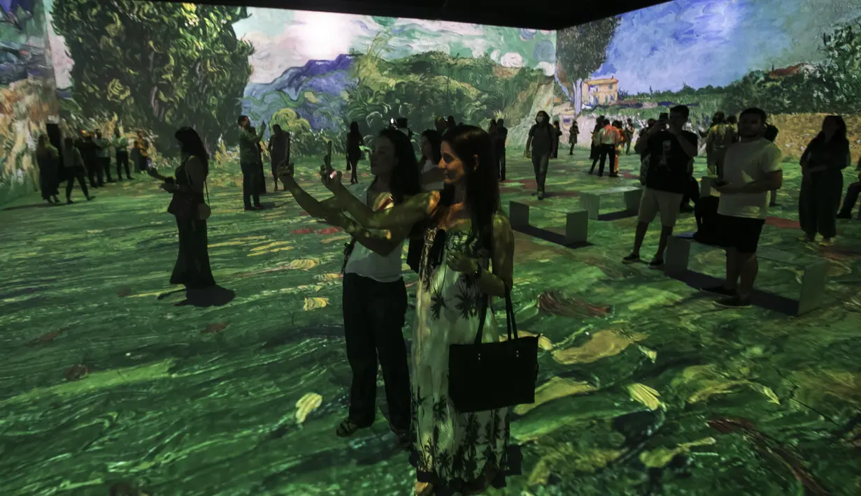 Para tamu dan jurnalis berdiri di pameran multimedia Van Gogh Live 8K yang menampilkan proyeksi lukisan seniman Belanda Vincent Willem van Gogh pada pembukaan pameran untuk media dan tamu di Rio de Janeiro, Brasil, Rabu (27/7/2022). (AP Photo / Bruna Prado)