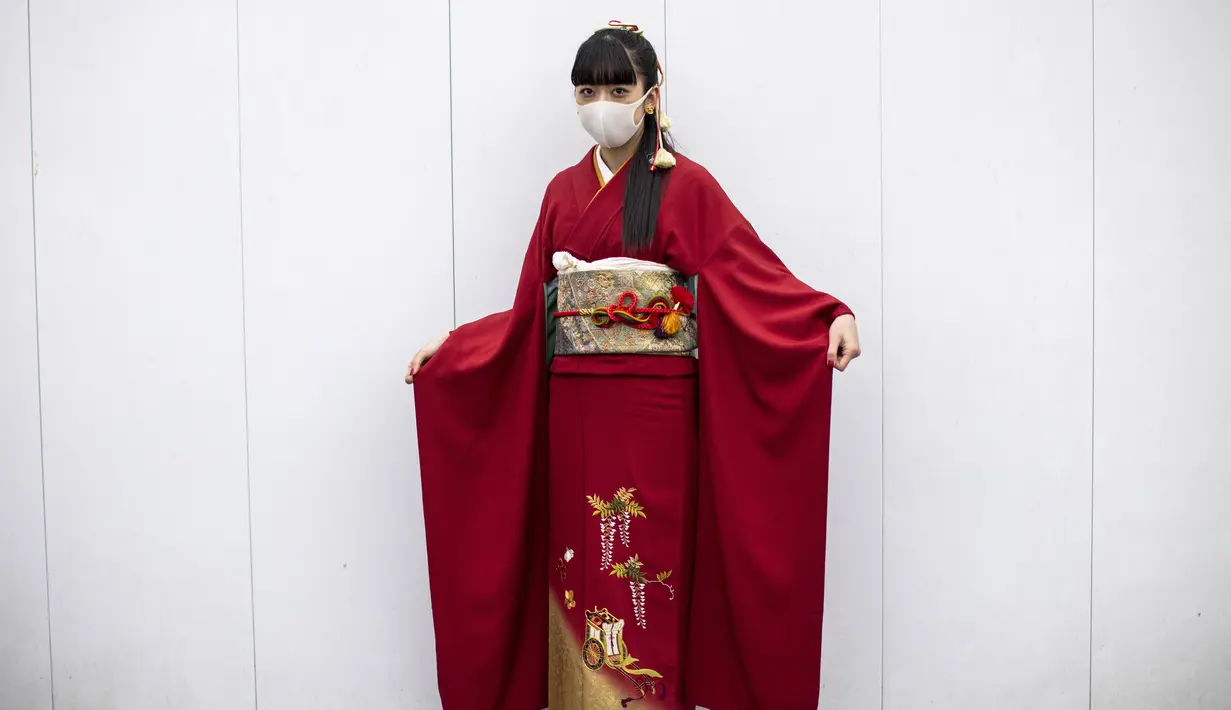 Rinka Okada berusia 20 tahun mengenakan kimono dan masker berpose di luar Todoroki Arena selama upacara perayaan "Coming-of-Age Day" di Kawasaki, prefektur Kanagawa (11/1/2021). (AFP/Behrouz Mehri)