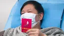 Pasien yang pulih dari coronavirus memegang sertifikat donor darah saat menyumbang plasma di Wuhan (17/2/2020). Pasien sembuh diimbau menyumbangkan plasma karena hasil awal mengindikasikan efektivitas produk terapeutik plasma konvalesen dalam mengobati pasien dengan kondisi kritis. (Xinhua/Cai Yang)