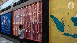 Seorang anak belajar perkalian dan pembagian melalui gambar mural di Jalan Pademangan 2, Jakarta, Senin (18/11/2019). Mural edukasi ini dikerjakan anak-anak muda yang tergabung dalam Tim Mural Pademangan Timur. (Liputan6.com/Faizal Fanani)