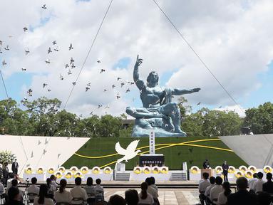 Merpati terbang di atas Patung Perdamaian selama upacara di Taman Perdamaian Nagasaki di Nagasaki, Jepang selatan, Senin (9/8/2021). Kota Nagasaki di Jepang pada hari Senin menandai peringatan ke-76 bom atom AS. (Kyodo News via AP)