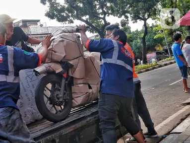 Pekerja tengah mengepak sepeda motor yang akan dikirim melalui jasa pengiriman dengan kereta api di Kawasan Stasiun Senen, Jakarta, Kamis (13/4/2023).(Liputan6.com/Angga Yuniar)