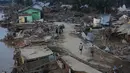 Data BPBD juga mencatat, korban meninggal dunia di Kabupaten Aceh Tamiang sebanyak 42 orang. Tampak dalam foto, para penyintas berjalan di area terdampak banjir bandang di Aceh Tamiang, Sumatera, Kamis 4 Desember 2025. (AP Photo/Binsar Bakkara)