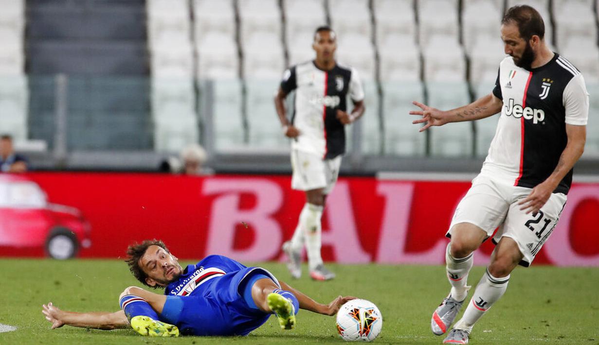Striker Juventus, Gonzalo Higuain, berusaha melewati pemain Sampdoria, Manolo Gabbiadini, pada laga Serie A di Allianz Stadium, Turin, Senin (27/7/2020). Kemenangan 2-0 ini membuat juventus mengunci gelar juara Serie A musim 2019-2020. (AP Photo/Antonio Calanni)