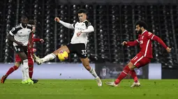 Pemain Fulham Antonee Robinson mencoba memblokir tembakan dari pemain Liverpool Mohamed Salah (kanan) pada pertandingan Liga Premier Inggris di Stadion Craven Cottage, London, Minggu (13/12/2020). Liverpool dan Fulham bermain imbang 1-1. (Neil Hall/Pool via AP)