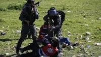 Tentara Israel menodongkan senjata ke petugas medis Palestina ketika berusaha mengobati demonstran yang terlibat bentrokan di Ramallah, Tepi Barat, Senin (12/3). Aksi protes terkait pengangkapan salah satu mahasiswa oleh pasukan Israel. (ABBAS MOMANI/AFP)