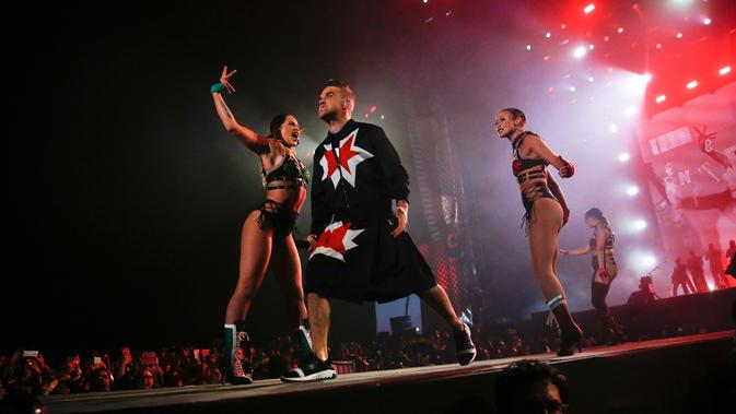 Aksi panggung Robbie Williams bersama para penari di Festival Musik Corona Capital di Meksiko (17/11). Pria 44 tahun ini tampil energik mengenakan setelan jas hitam dan rok yang dihiasi bintang merah. (AP Photo/Eduardo Verdugo)