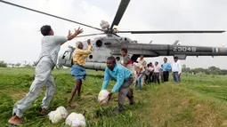 Warga korban banjir mendistribusikan bantuan paket makanan dari helikopter Angkatan Udara India di pinggiran Allahabad, India, Kamis. (25/08). Korban tewas akibat banjir menjelang akhir Agustus ini telah mencapai 300 orang (REUTERS / Jitendra Prakash)