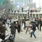 Massa aksi demo mahasiswa berlari menghindari tembakan gas air mata oleh aparat keamanan di depan Gedung DPR, Jakarta, Senin (11/4/2022). Mahasiswa yang tergabung dalam aliansi BEM SI menggelar unjuk rasa besar-besaran di depan Gedung DPR/MPR RI, Senin ini. (Liputan6.com/Angga Yuniar)