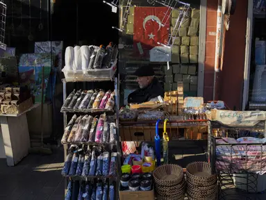 Seorang pria duduk di sebelah barang-barang yang dijual di pasar di distrik Fatih Istanbul, Turki, Selasa, 3 Januari 2023.  Inflasi Turki pada Desember 2022 turun drastis. Hal itu dinilai dapat mendukung posisi Presiden Recep Tayyip Erdogan jelang pemilu pada tahun ini. (AP Photo/Khalil Hamra)