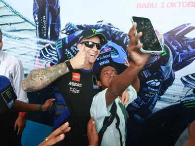 Pembalap Monster Energy Yamaha, Fabio Quartararo, foto bersama siswa saat mengunjungi SMAN 2 Mataram, Nusa Tenggara Barat (NTB), Rabu (1/10/2025). (Bola.com/M Iqbal Ichsan)