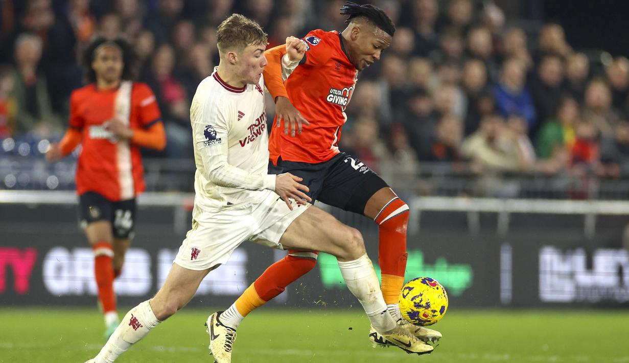 Pemain Manchester United, Rasmus Hojlund, berebut bola dengan pemain Luton Town, Gabriel Osho, dalam duel pekan ke-25 Premier League di Kenilworth Road, Minggu (18/2/2024). Tahun 2024 sudah hampir berjalan dua bulan dan Manchester United belum tersentuh kekalahan. (AP Photo/Ian Walton)