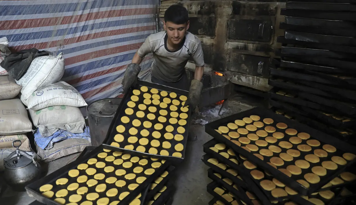 Seorang tukang roti Afghanistan menumpuk nampan berisi penganan manis di toko roti tradisional menjelang bulan puasa Ramadan mendatang, di Kabul, Afghanistan, pada 7 April 2021. Sebentar lagi, umat Muslim di seluruh dunia akan menyambut bulan Ramadan.  (AP Photo / Rahmat Gul)