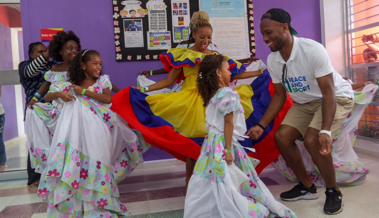 Mantan pesebak bola dunia Didier Drogba menari bersama anak-anak saat melakukan acara amal organisasi internasional Peace and Sport, di Cartagena, Kolombia (19/3). (Cesar Carrion/Colombian Presidency/AFP)