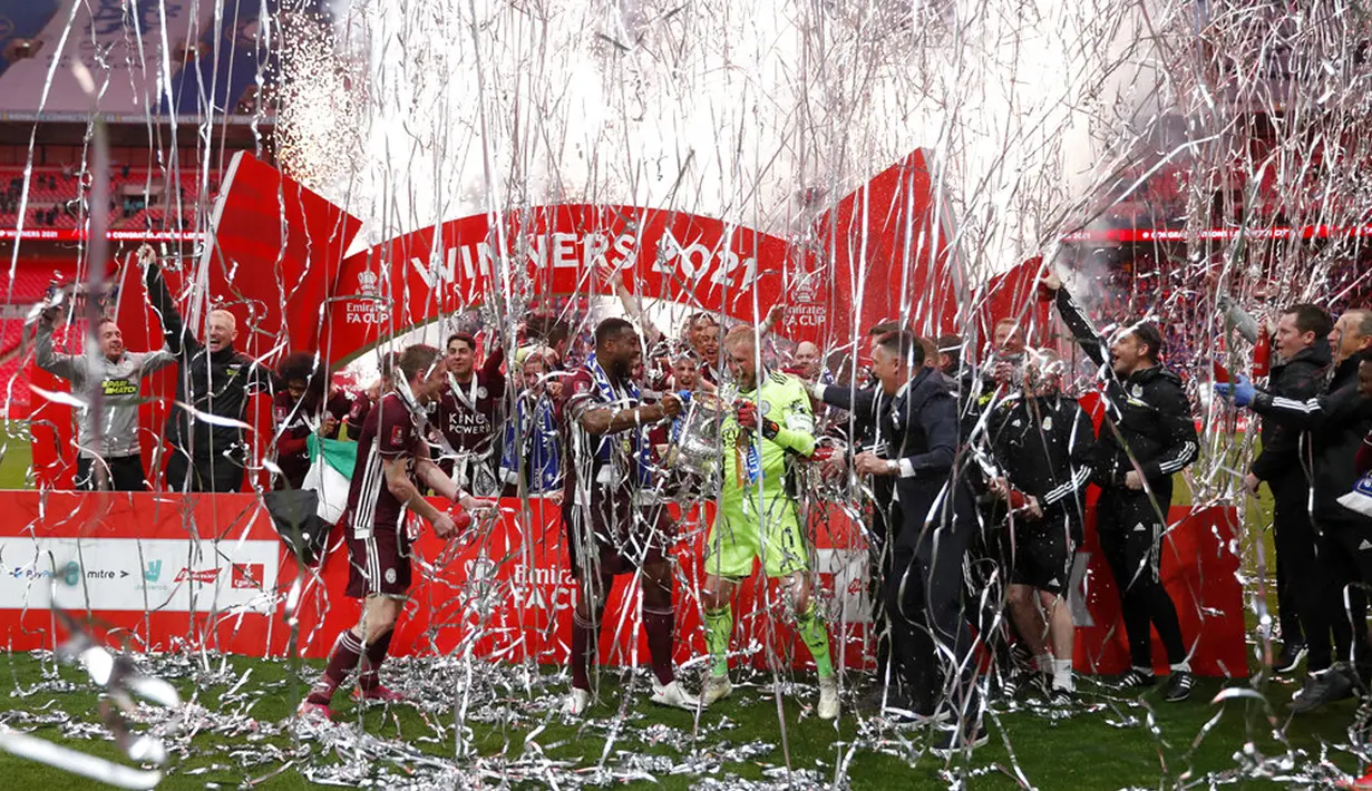 Penjaga gawang Leicester City Kasper Schmeichel (tengah kanan) dan Wes Morgan memegang trofi Piala FA usai mengalahkan Chelsea pada pertandingan final di Stadion Wembley, London, Inggris, Sabtu (15/5/2021). Leicester City mengalahkan Chelsea 1-0. (Matt Childs/Pool via AP)