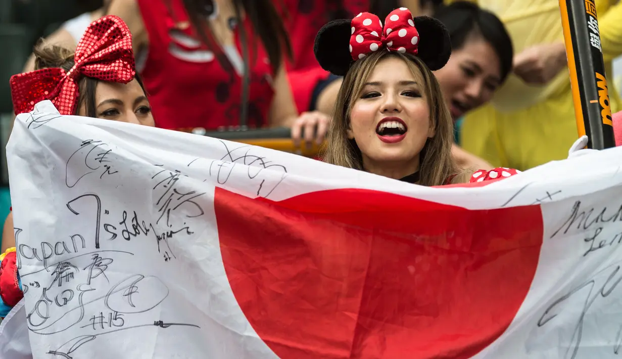 Fans wanita membawa bendera negara Jepang saat menyaksikan pertandingan RugbY Sevens di Hong Kong (9/4). Para wanita yang  ini hadir mengenakan pakaian dan atribut unik demi mendukung tim kesayangannya. (AFP Photo / Dale De La Rey)