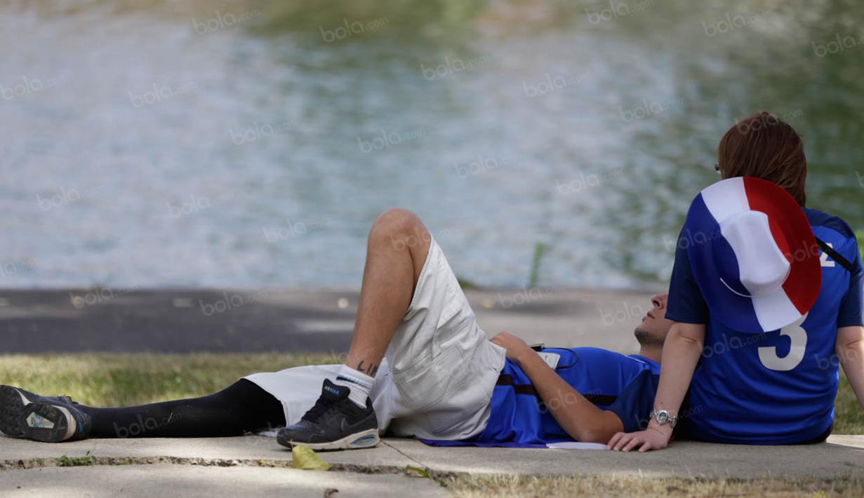 Sejoli pendukung Prancis bersantai di tepi sungai sebelum masuk ke Stadion Stade de France menyaksikan laga final Piala Eropa 2016. (Bola.com/Vitalis Yogi Trisna)
