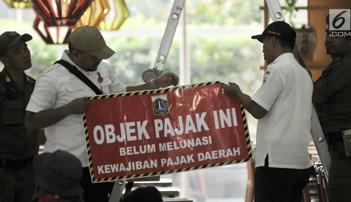 Tim gabungan dari Badan Pelayanan Pajak, Kecamatan Cempaka Putih, dan Satpol PP menyiapkan stiker tunggak pajak di salah satu kios Green Pramuka Square Mall, Jakarta, Rabu (7/11). (Merdeka.com/Iqbal S. Nugroho)