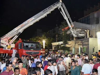 Warga berkumpul saat petugas pemadam berusaha mengevakuasi korban yang terjebak kebakaran  besar di rumah sakit SUM Bhubaneshwar di Odisha, India Timur, Senin (17/10). Sedikitnya 19 orang tewas dan sejumlah lainnya cedera dalam peristiwa tersebut. (AFP)