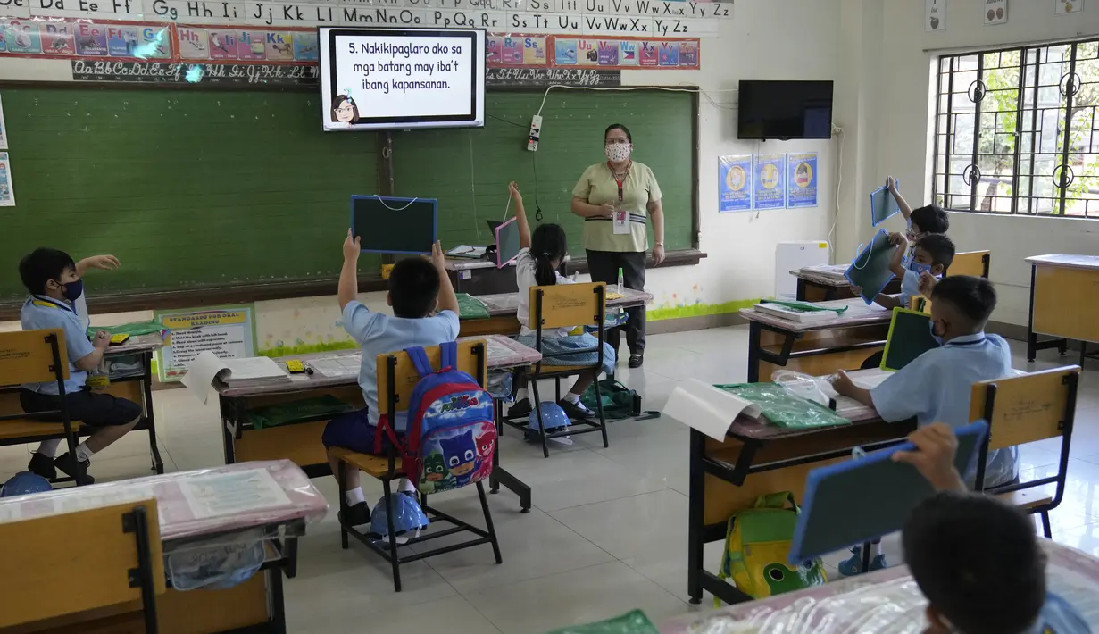 Para siswa mengenakan masker selama hari pertama kelas tatap muka di sekolah dasar Comembo di kota Makati, Filipina, Senin (6/12/2021). Beberapa sekolah di Manila diizinkan dibuka kembali setelah berbulan-bulan lamanya karena kasus COVID-19 terus menurun di negara tersebut (AP Photo/Aaron Favila)