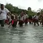 Puluhan siswa dibantu kepala desa, aparat desa dan guru saat menyebrangi sungai.(Liputan6.com/Dionisius Wilibardus)